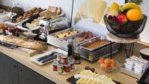 A buffet with various food items including bread, pastries, fruits, and condiments. - Hôtel Palais De Chaillot (Paris)