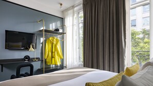 A modern hotel room with a large bed, a TV mounted on the wall, a desk with a chair, and a window with curtains. - Hôtel Palais De Chaillot (Paris)