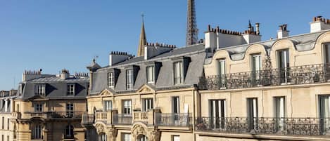 Una hilera de edificios históricos de estilo europeo, con fachadas ornamentadas, varios balcones y una imponente estructura de torre al fondo.