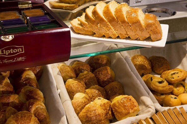 A variety of pastries displayed in a glass case, including croissants and other baked goods. - Europe Hotel Paris Eiffel (Paris)