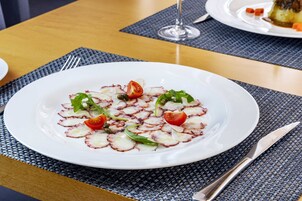 A white plate with octopus salad on a woven placemat.