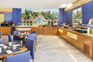 Et hotellets morgenmadsområde med buffet, siddepladser og et muralmaleri.