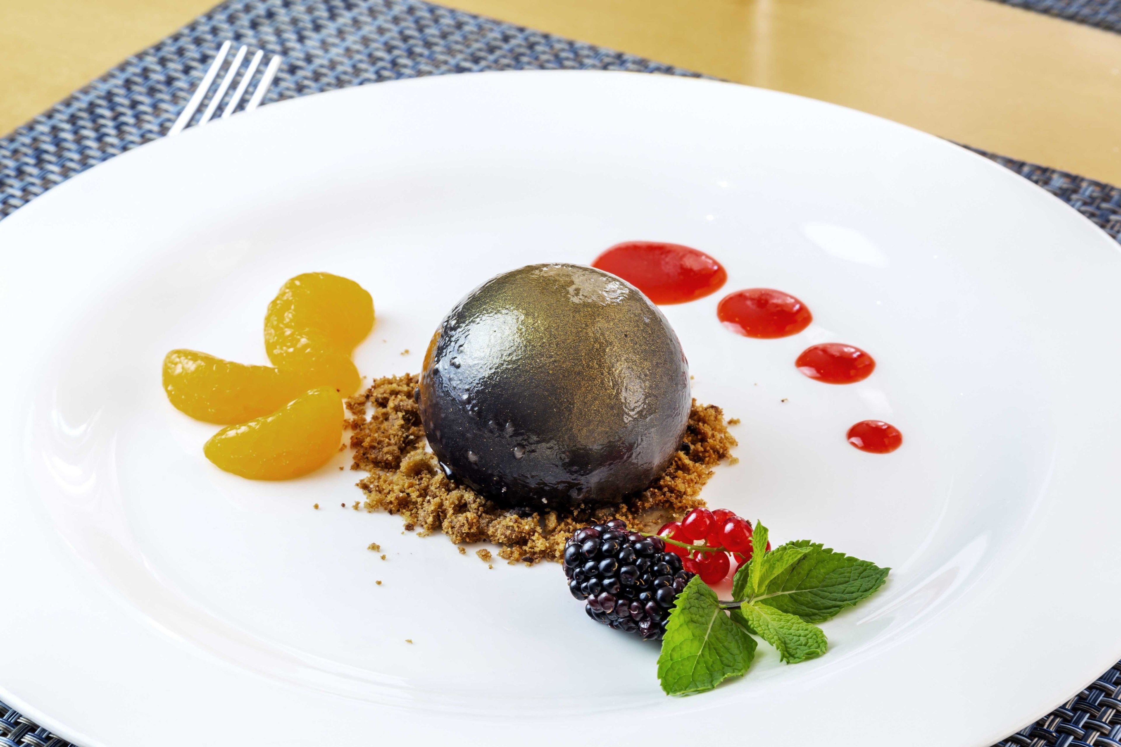 A dessert on a white plate with fruit and mint leaves.