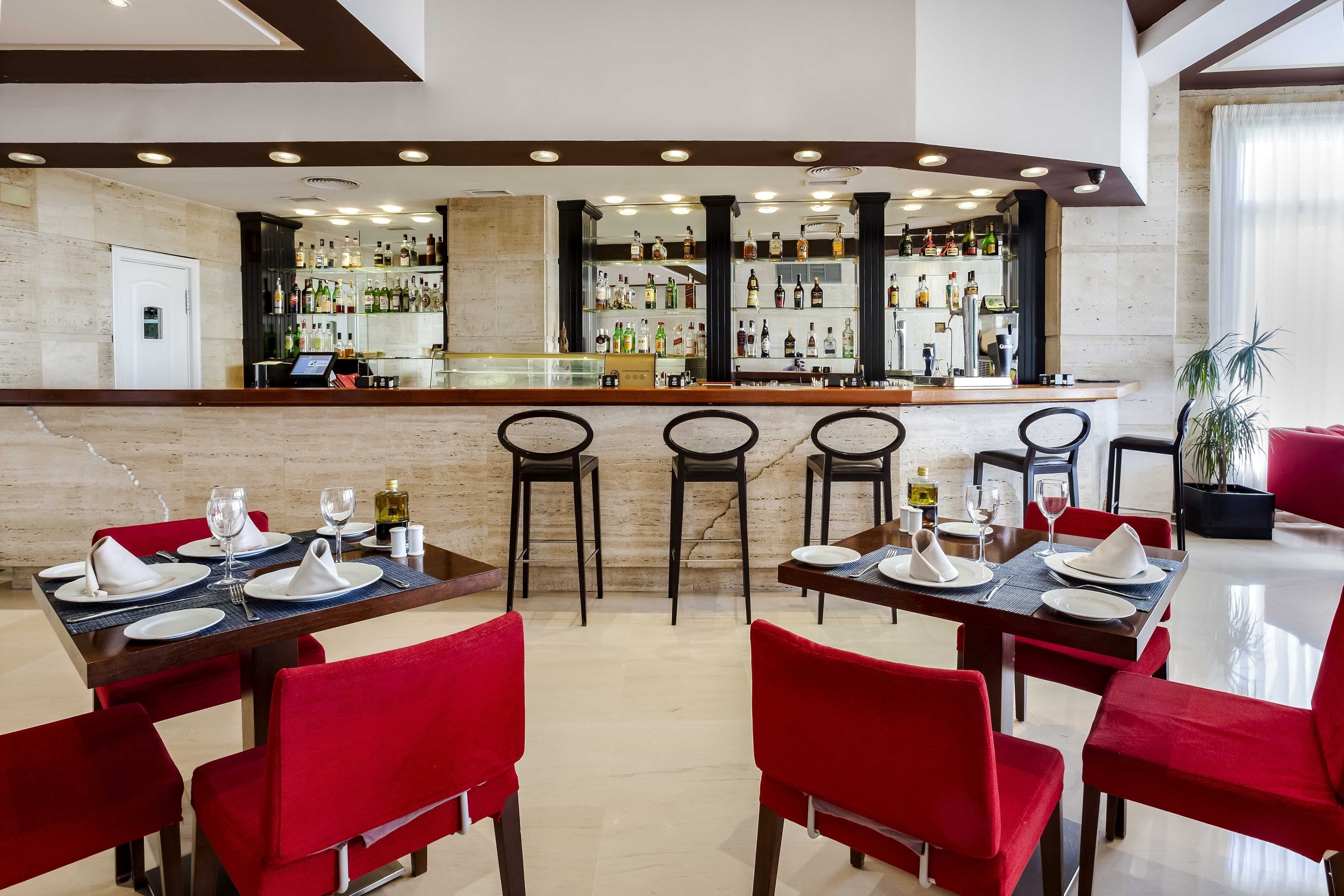 En restaurang med en bardel, röda stoppade stolar och ett marmorgolv.