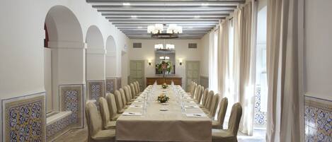 A long conference table with chairs, a chandelier, and a mirror in the background.