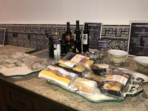 Una mesa de buffet con diversos alimentos, entre ellos pan, queso y aderezos.