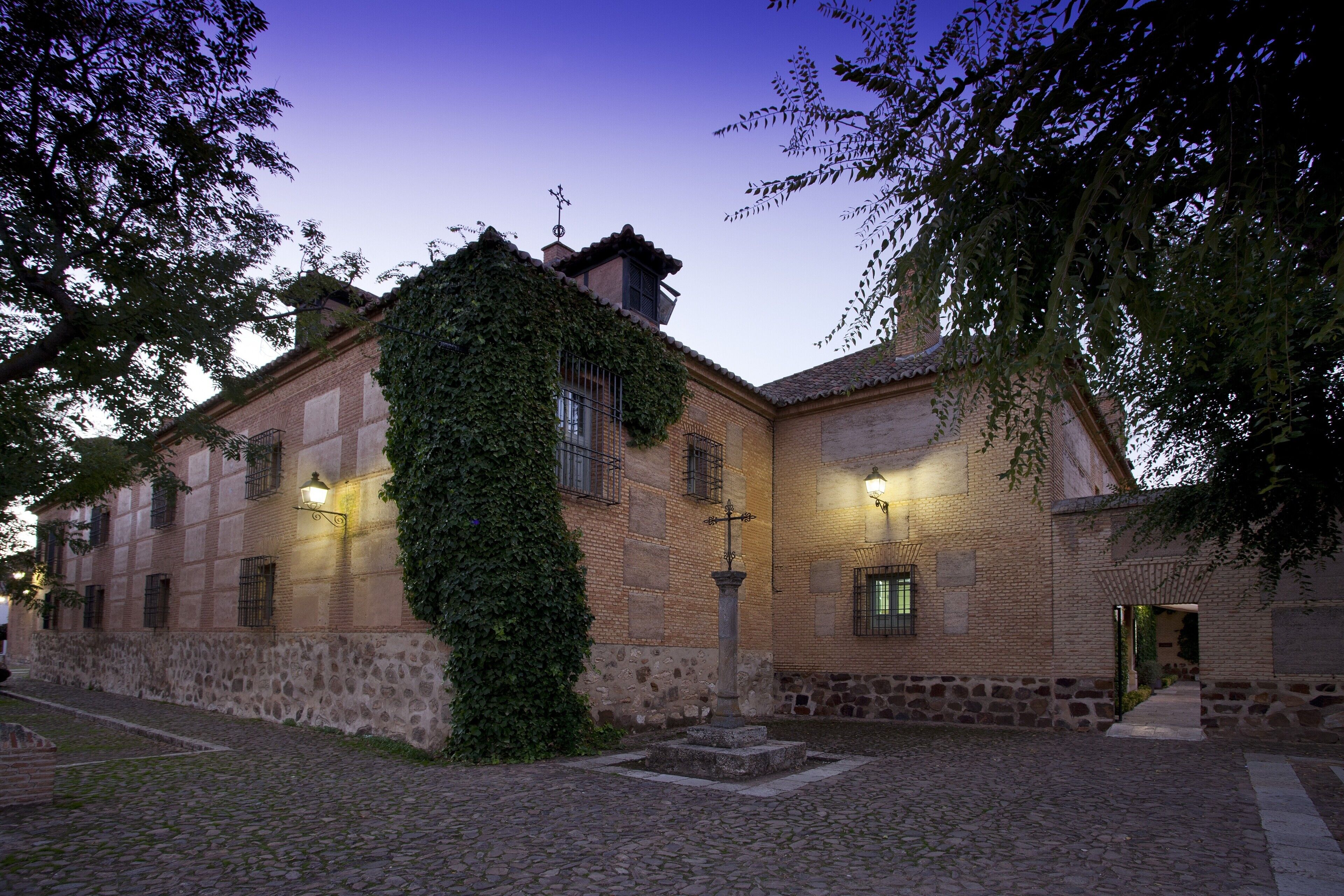 Un edificio histórico con un patio adoquinado, muros de piedra y fachada de ladrillo.