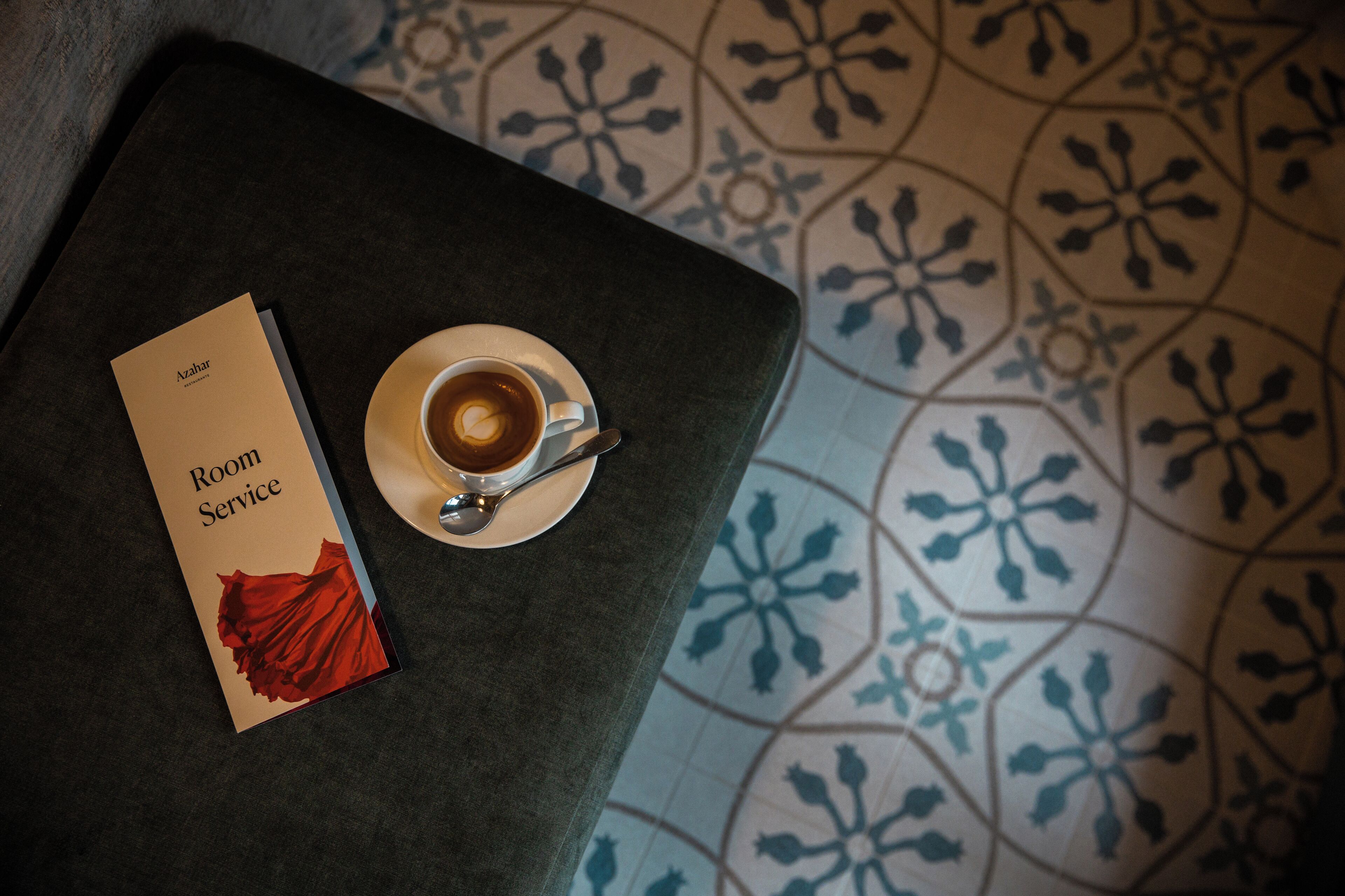 Un menu de service en chambre et une tasse de café sur une table, le tout posé sur un sol à motifs.