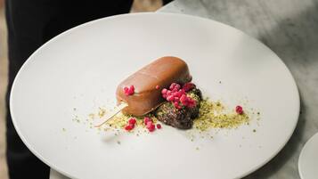 Iemand serveert een dessert op een wit bord.