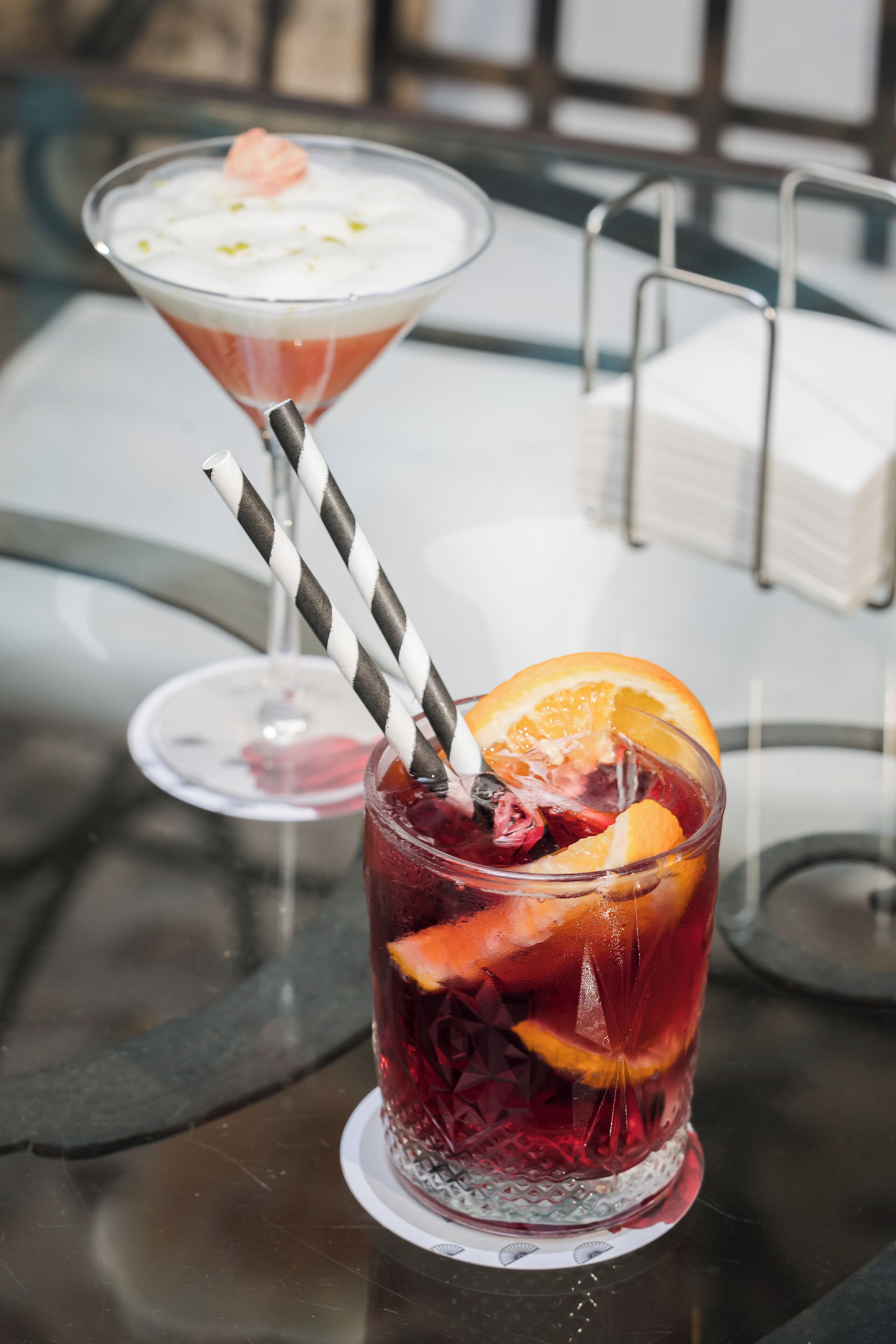 Ein Tisch mit zwei Getränken, eines in einem Martini-Glas und eines in einem Glas mit Trinkhalm.