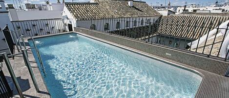 Alberca al aire libre, sombrillas en la alberca y camastros