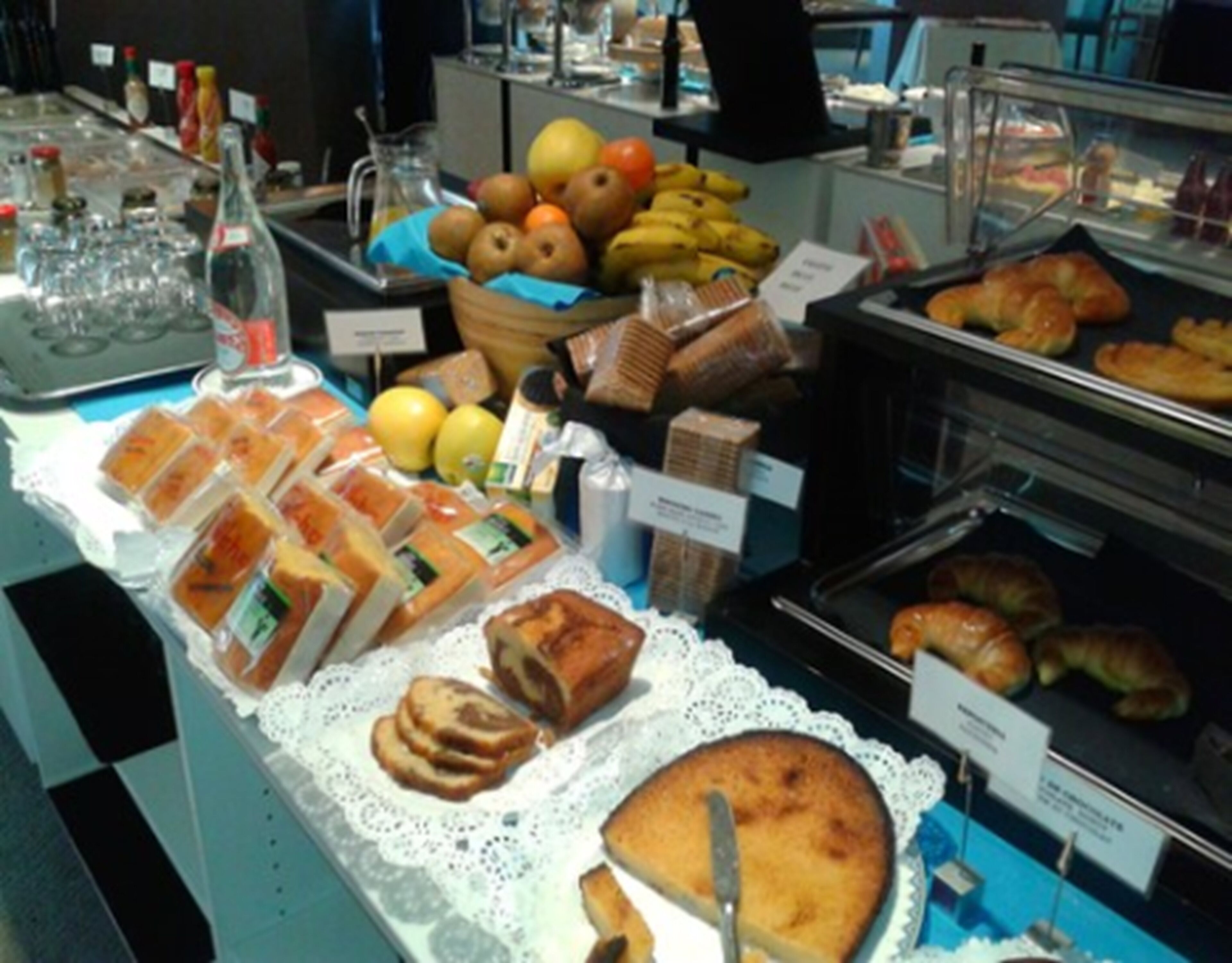 Un bufé con diferentes opciones de comida, incluyendo frutas, pasteles y pan.