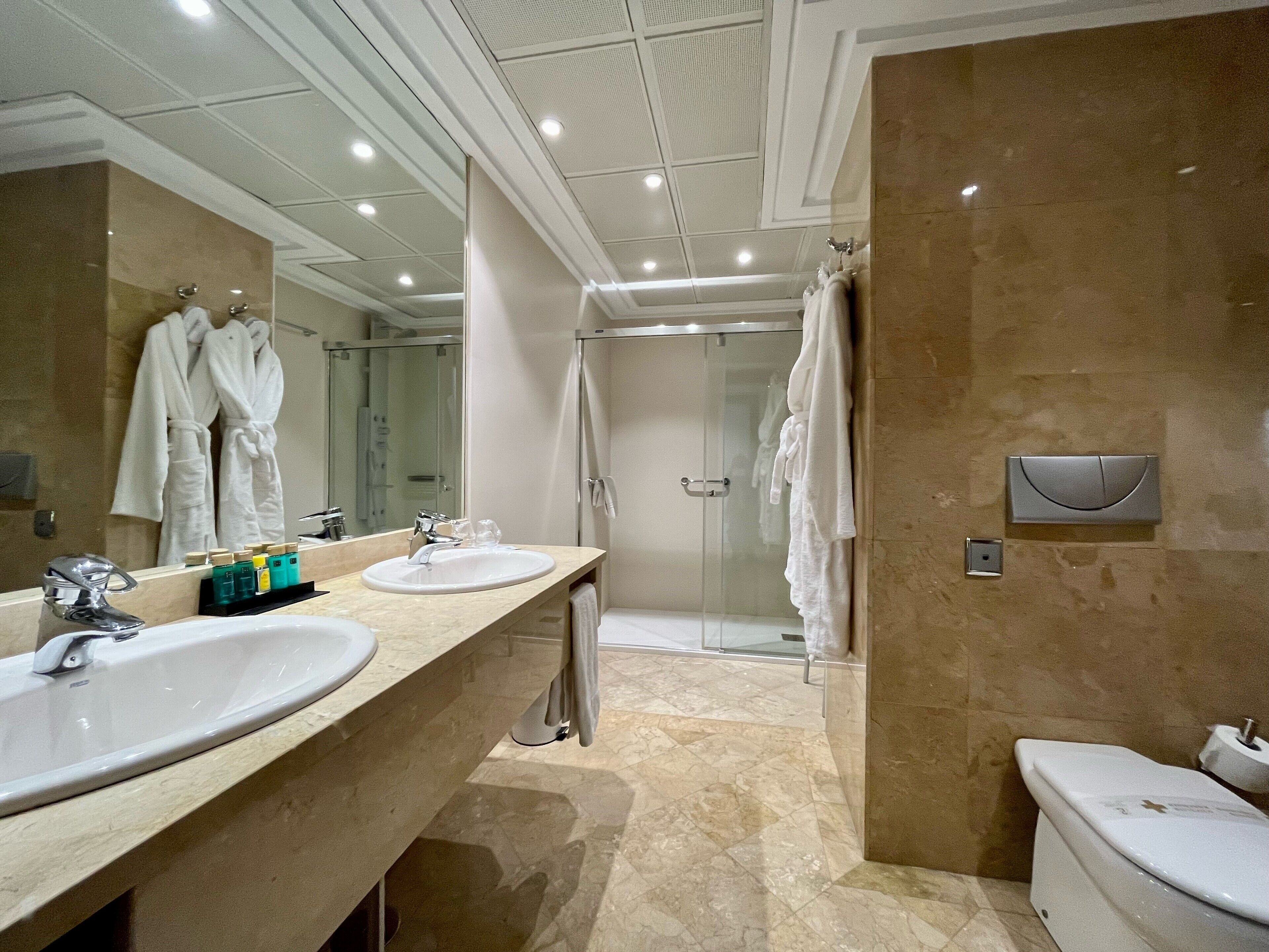 Ein modernes Badezimmer mit zwei Waschbecken, einer Glasdusche und einer Toilette.
