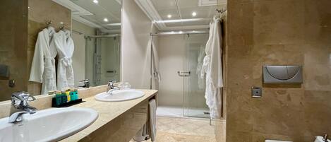 A modern bathroom with two sinks, a glass shower enclosure, and a toilet.
