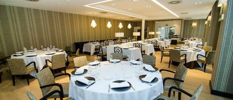 Un salón de conferencias con mesas redondas, sillas y mesas dispuestas para una reunión.