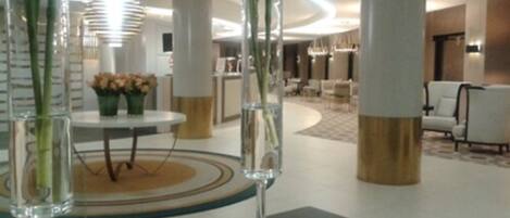 A modern lobby with a round table, vases, and a chandelier.