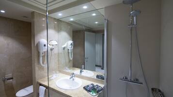 Un baño moderno con tocador con vidrio, ducha e inodoro.