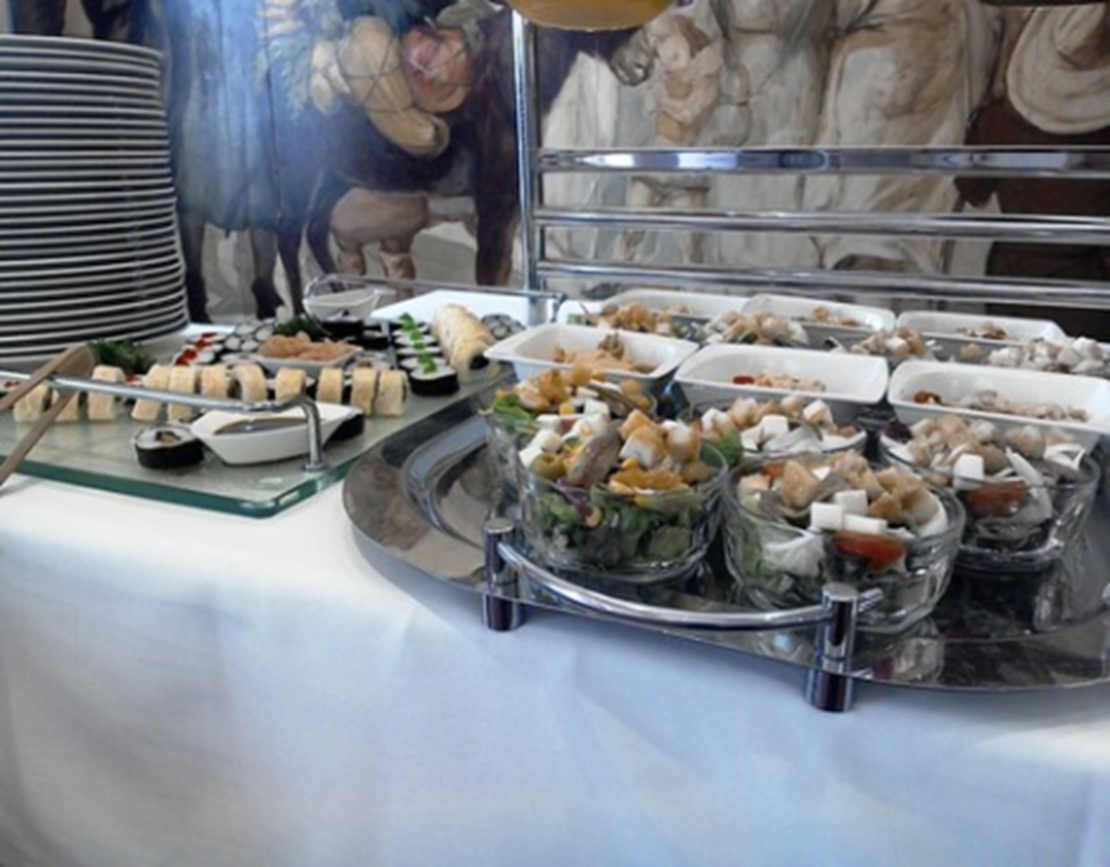 Buffet com diversos alimentos e uma pintura decorativa ao fundo.