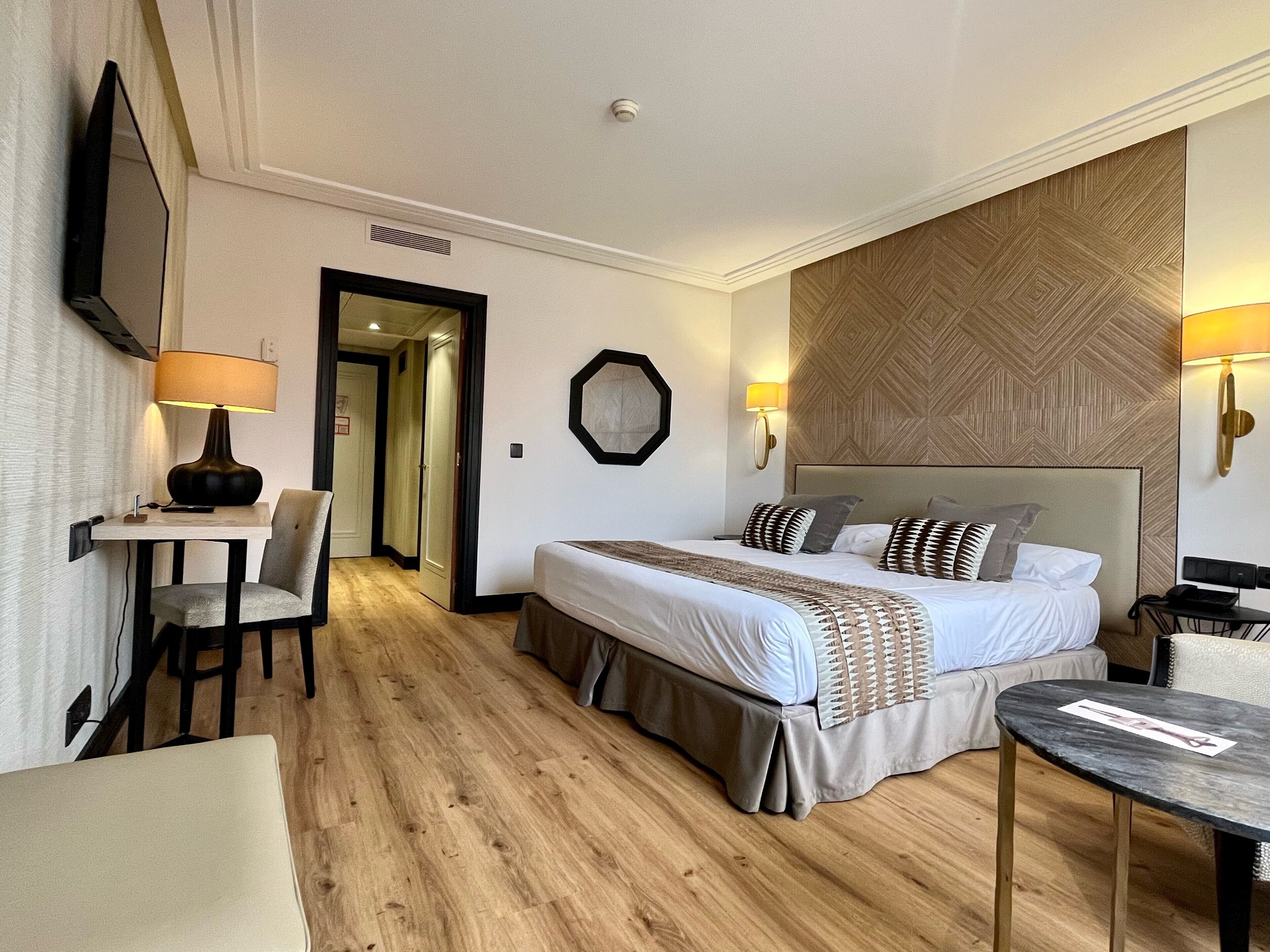 Una habitación de hotel con cama, mesitas de noche, escritorio y una silla.