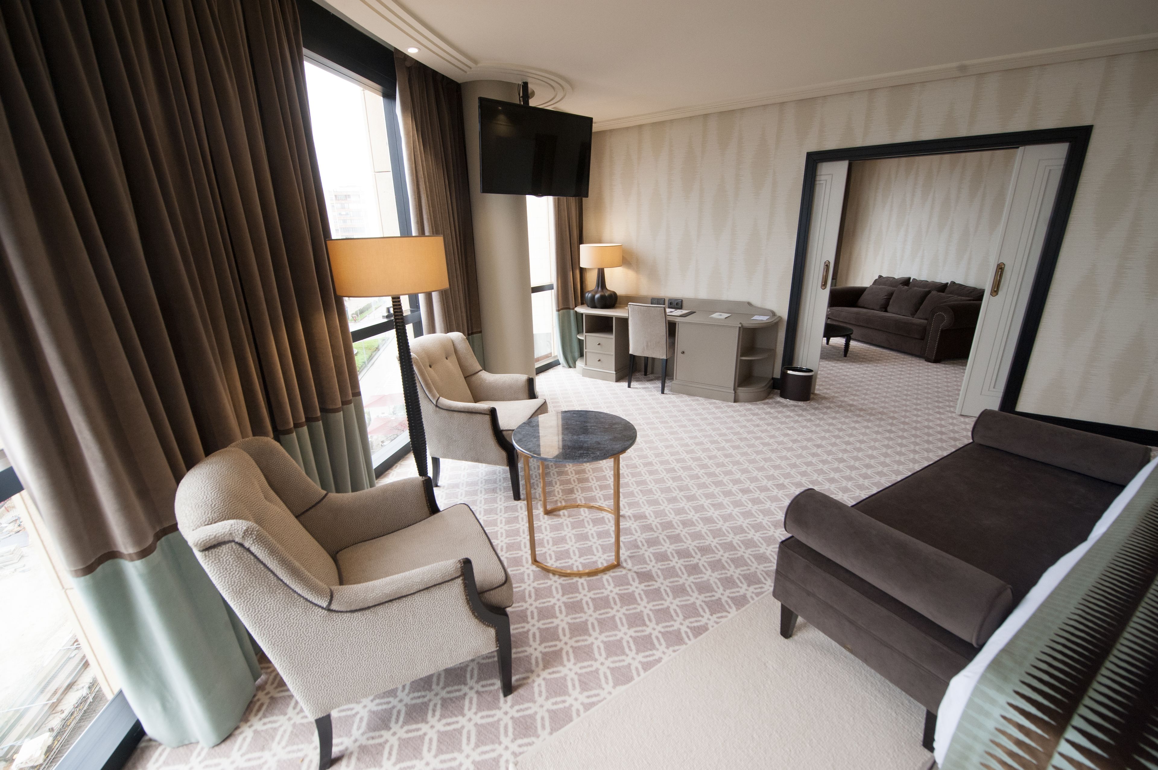 Una habitación de hotel con sofá, sillón, escritorio y televisi ón.