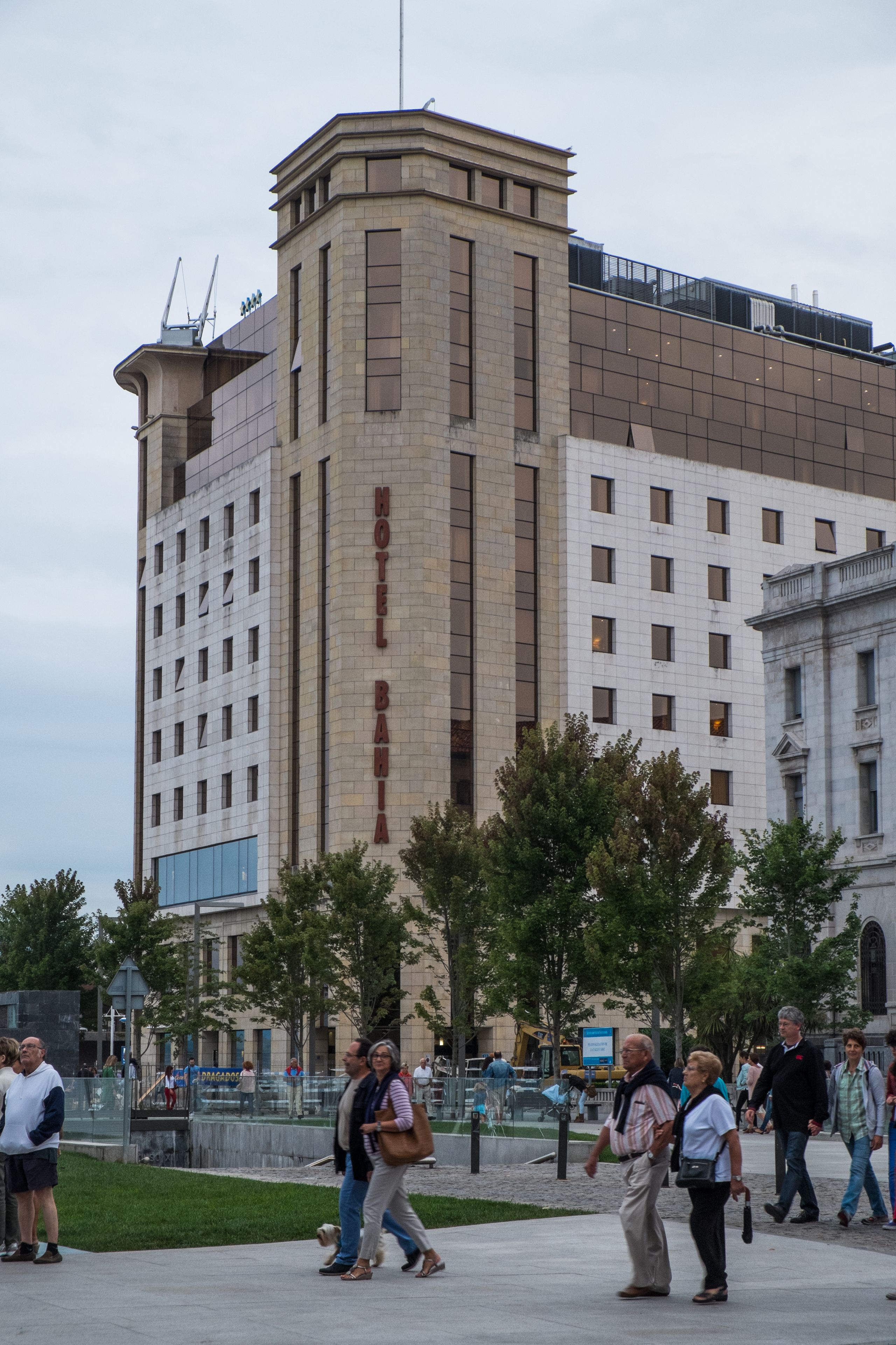 A hotel with a prominent 'Motel Bahia' sign, a modern architectural style, and a surrounding urban environment with pedestrians.