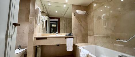 A modern bathroom with a large bathtub, a sink, and a mirror.