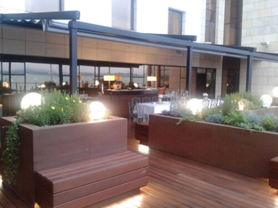Un espace extérieur aménagé avec un sol en bois et des jardinières remplies de plantes vertes.