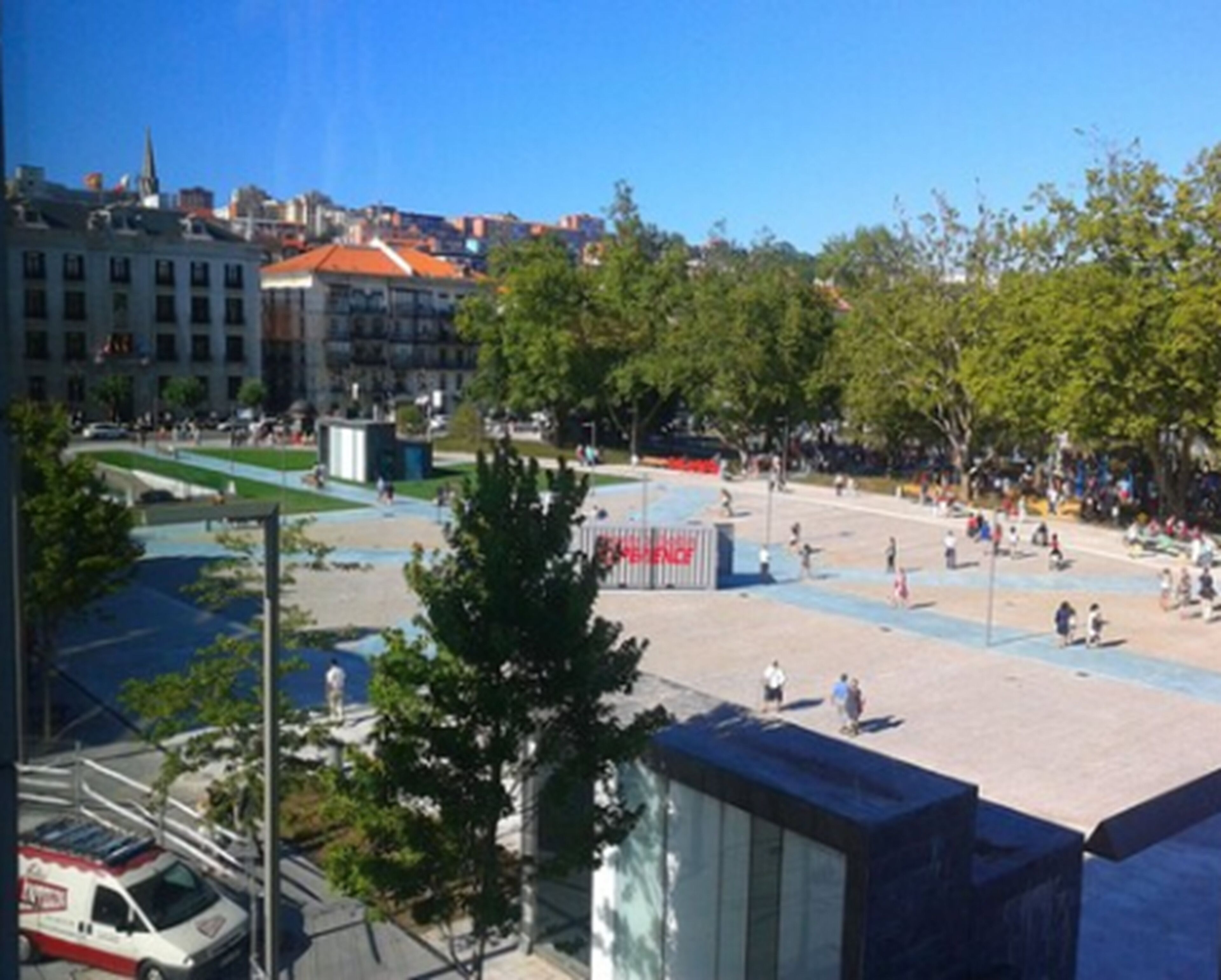 Una plaza pública con una fuente, zonas de descanso y una parada de autobús.