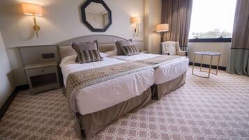 Une chambre d’hôtel avec un grand lit, deux tables de chevet, une chaise et une petite table.