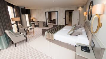 Une chambre d’hôtel avec un grand lit, un bureau, une chaise, un canapé et une télévision.