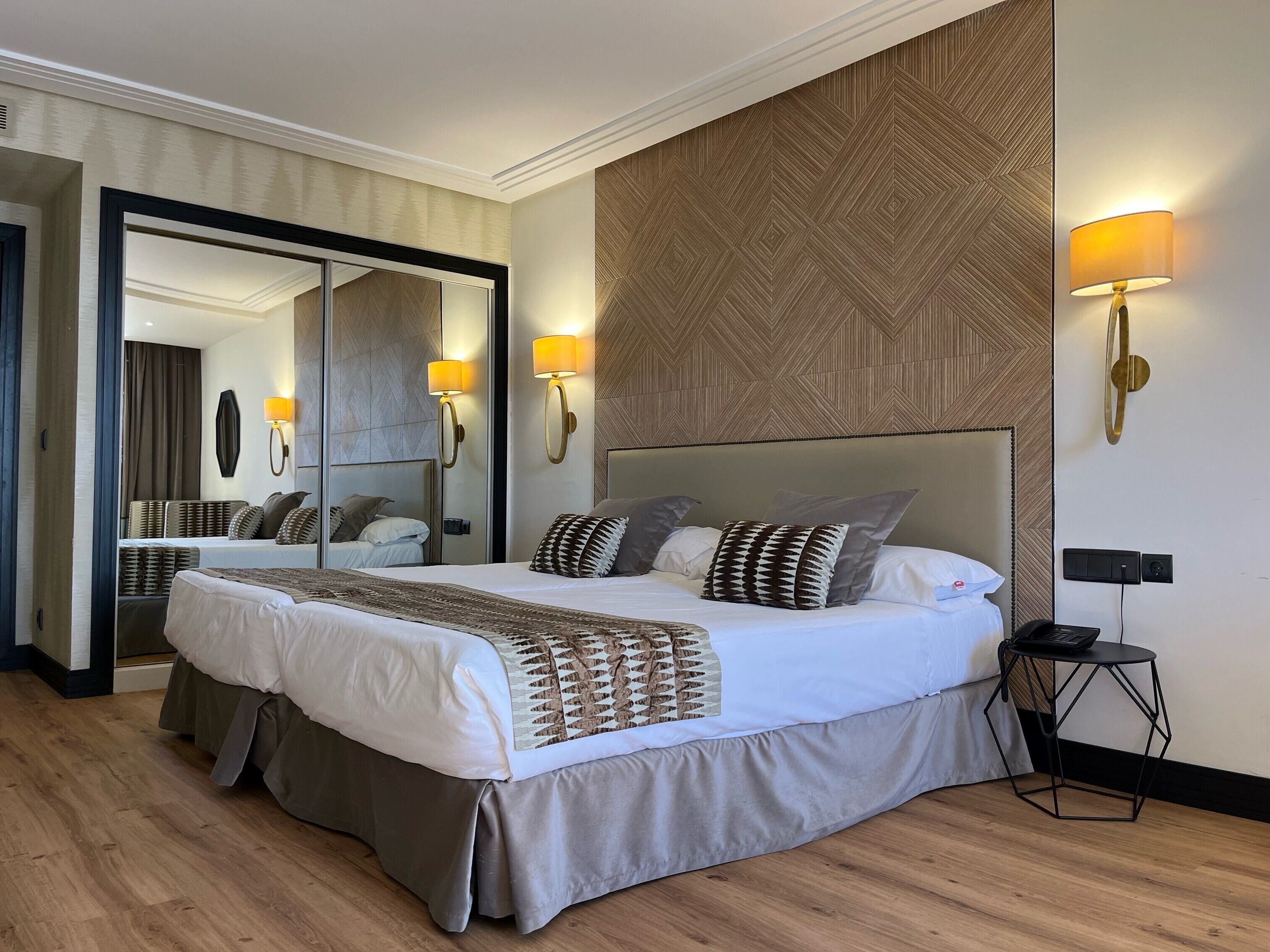 Une chambre d’hôtel avec un grand lit, deux lampes de chevet, un miroir et une petite table d’appoint.