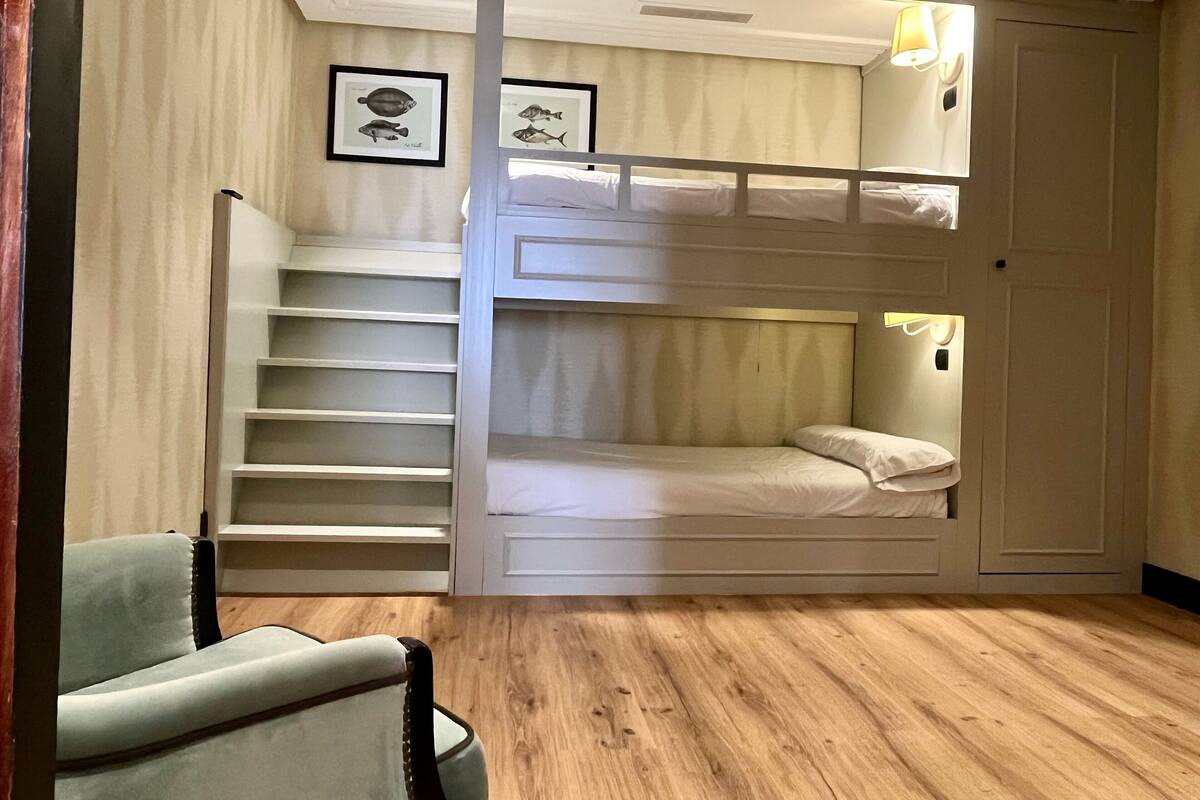 Una habitación con literas, una silla y una escalera.