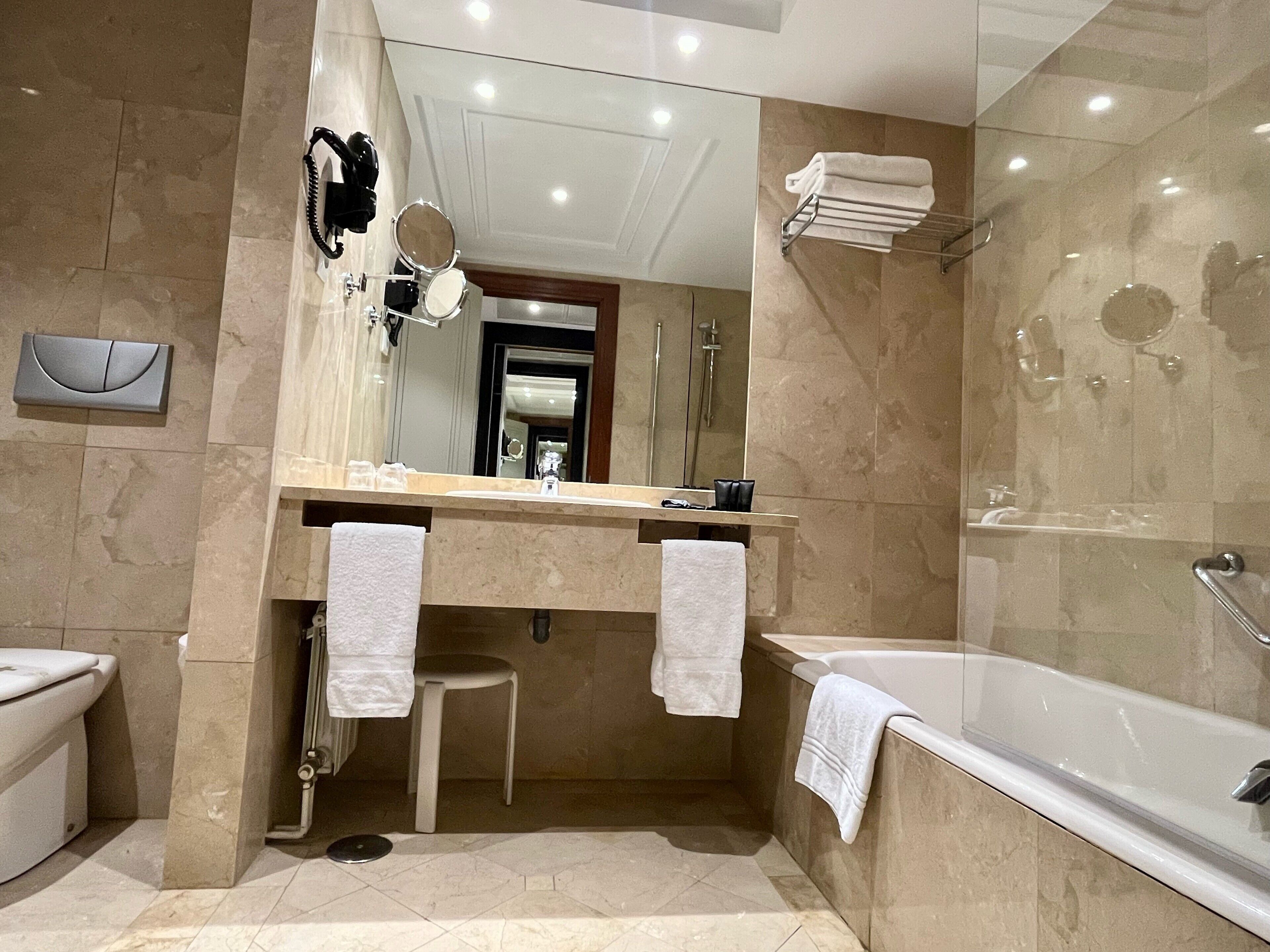 Un baño moderno con bañera, lavabo con espejo y zona de ducha.