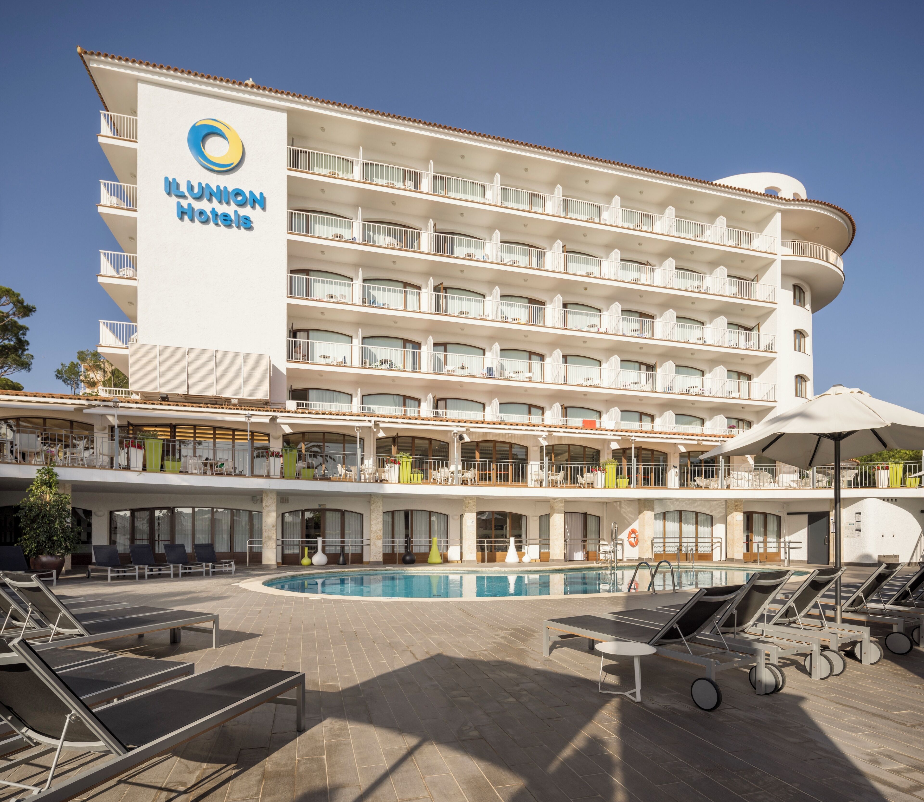 Et hotel med flere etager, en swimmingpool, udendørs siddepladser og altaner.
