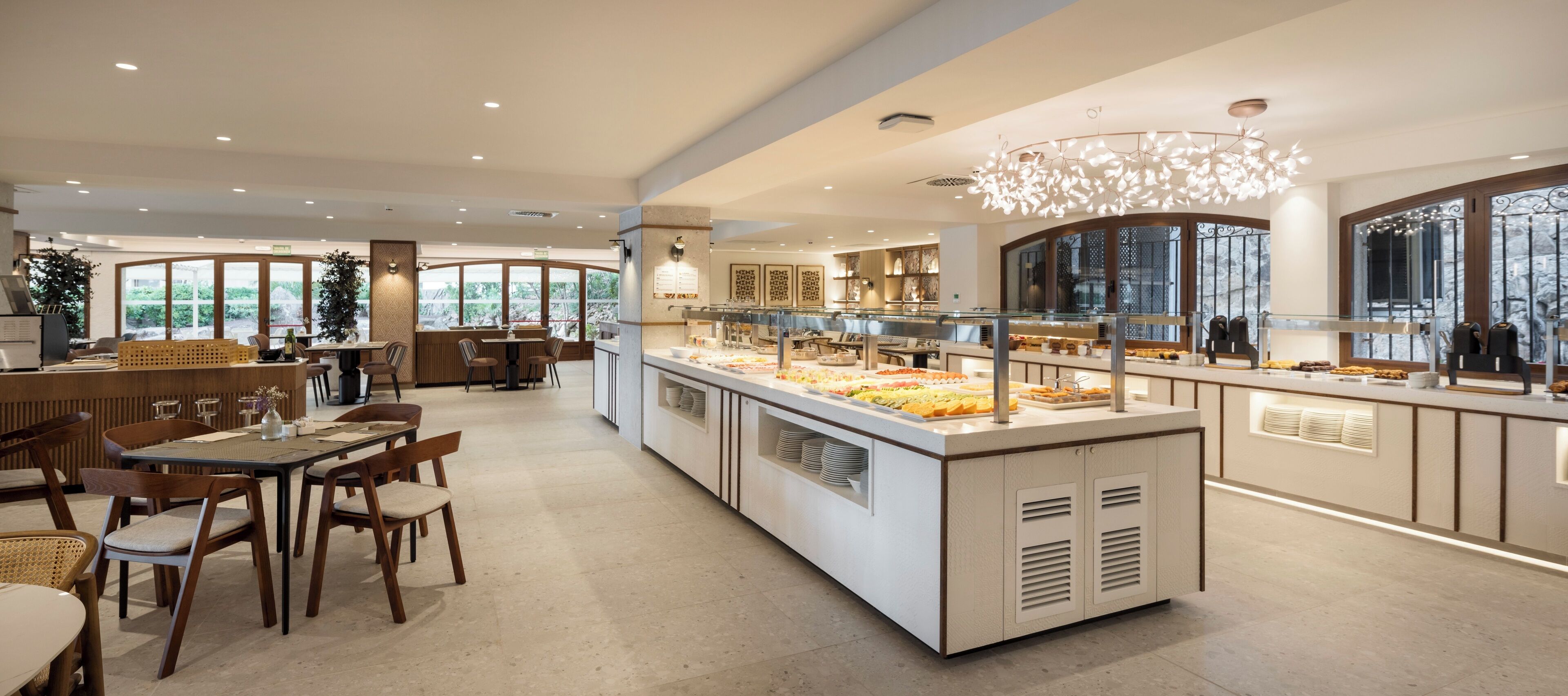 A modern dining area with a buffet counter, wooden chairs, and a large window providing a view of the outdoors.