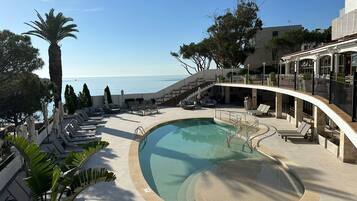 Una piscina al aire libre, sombrillas, tumbonas