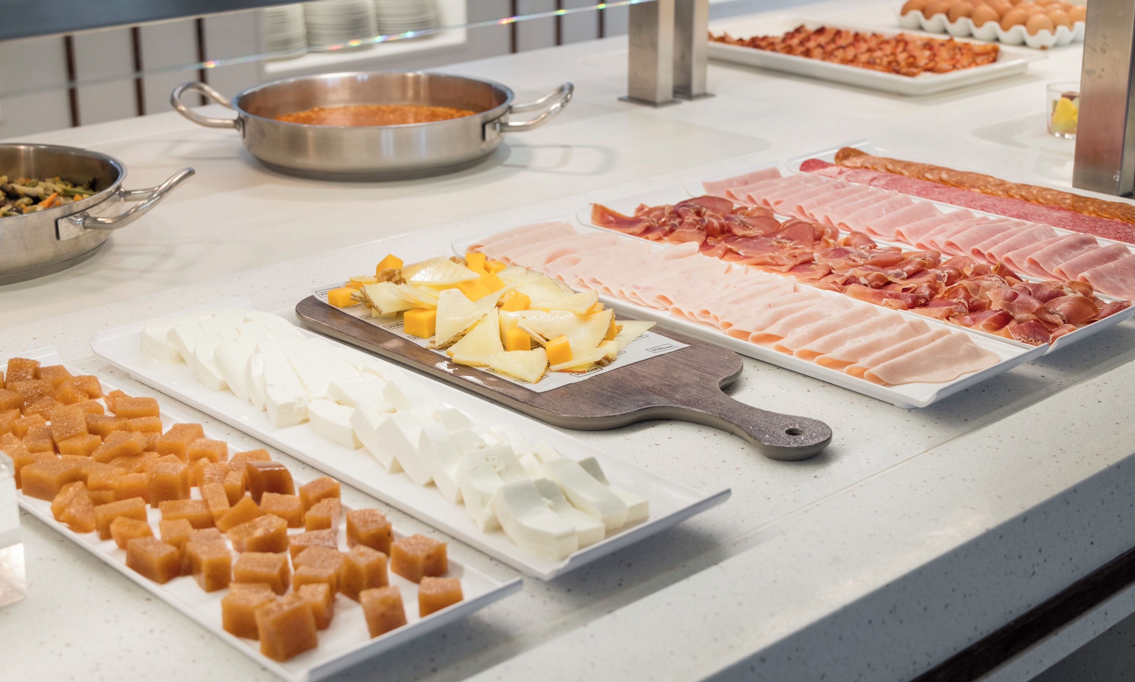 Un bufé con diversas opciones de comida, incluyendo carnes, quesos y frutas.