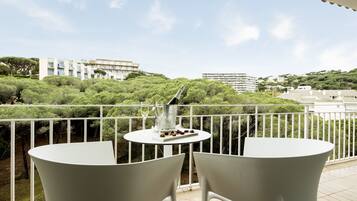 A balcony with two white chairs, a small table, and a bottle of wine.
