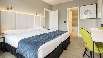 Una habitación de hotel moderna con una cama grande, un escritorio con una silla, y un baño visible a través de una puerta abierta.