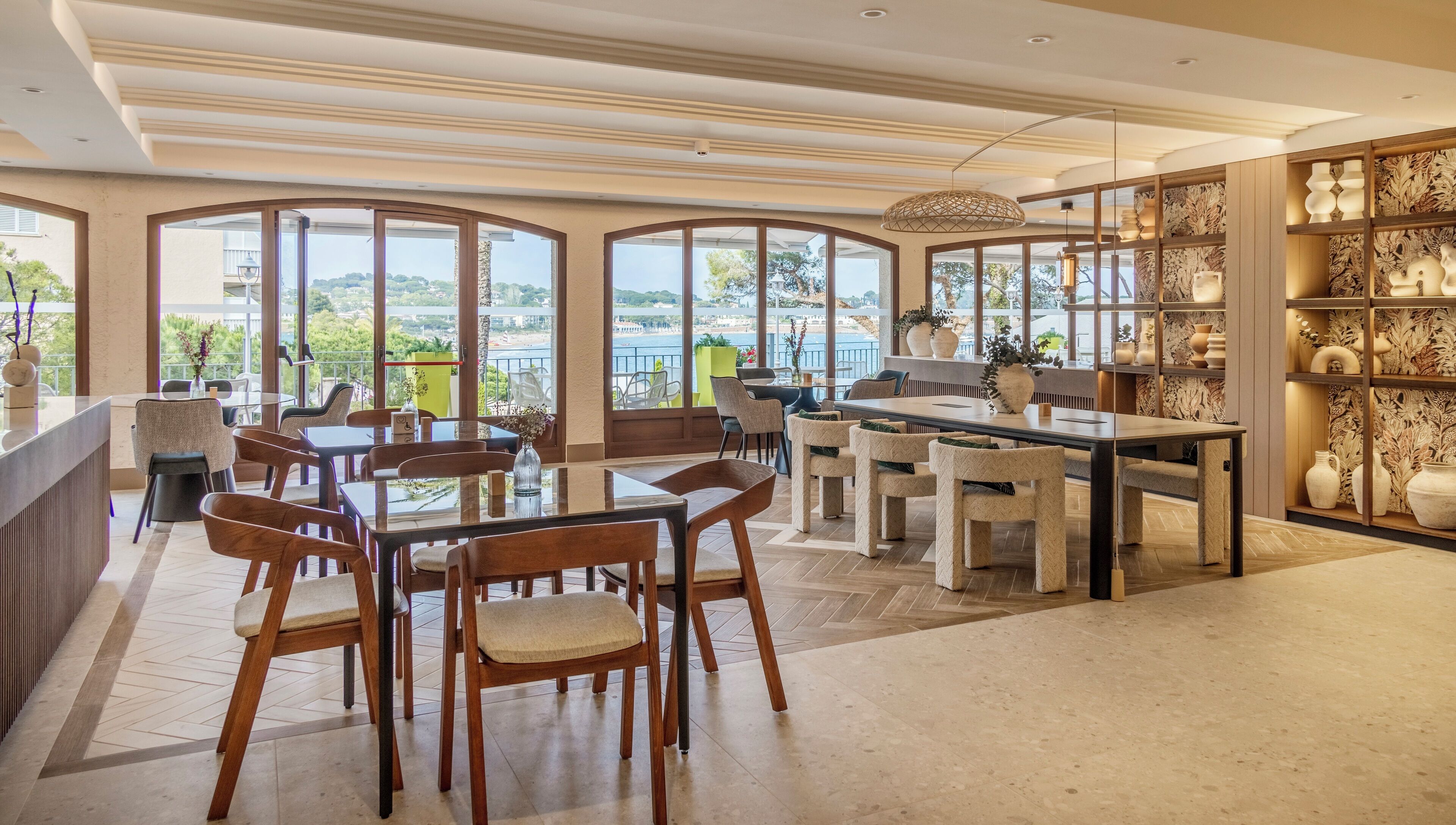 A spacious dining area with large windows, a central table, and chairs.