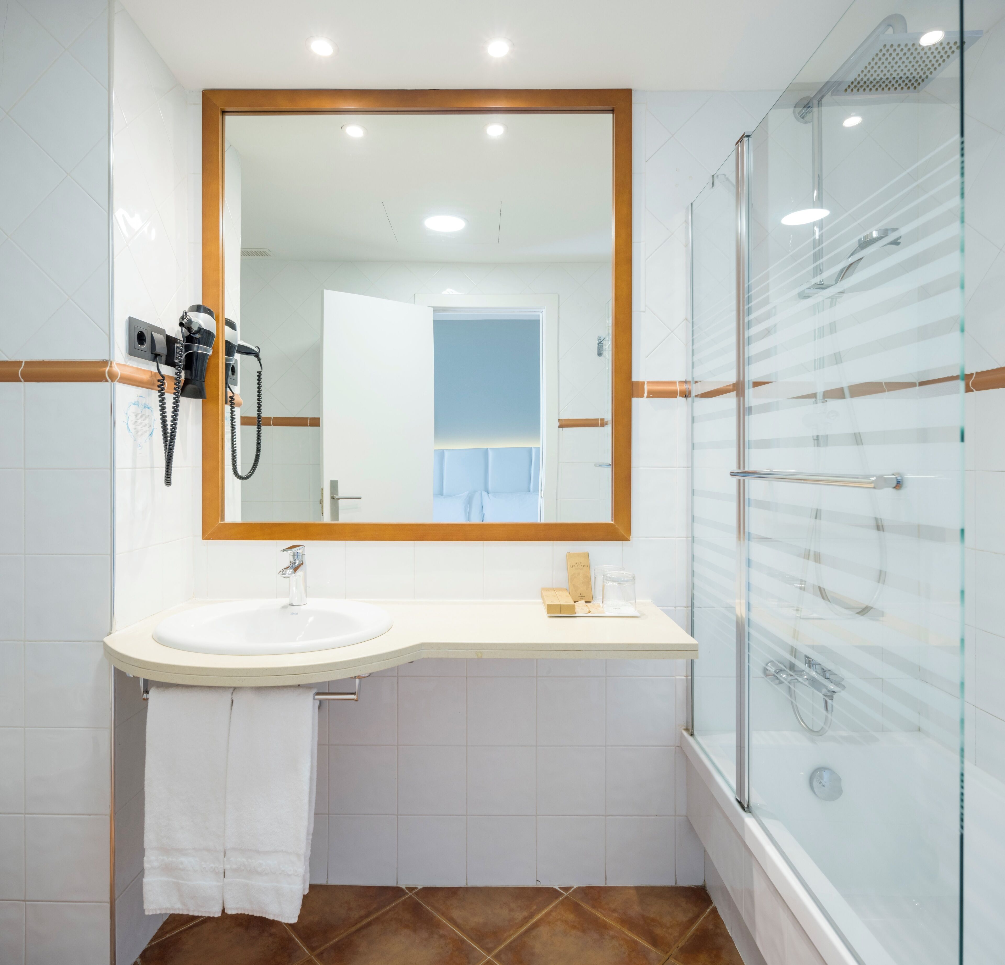 Un baño moderno con un espejo grande, un lavabo, cabina de ducha de vidrio y una toalla colgada en la pared.