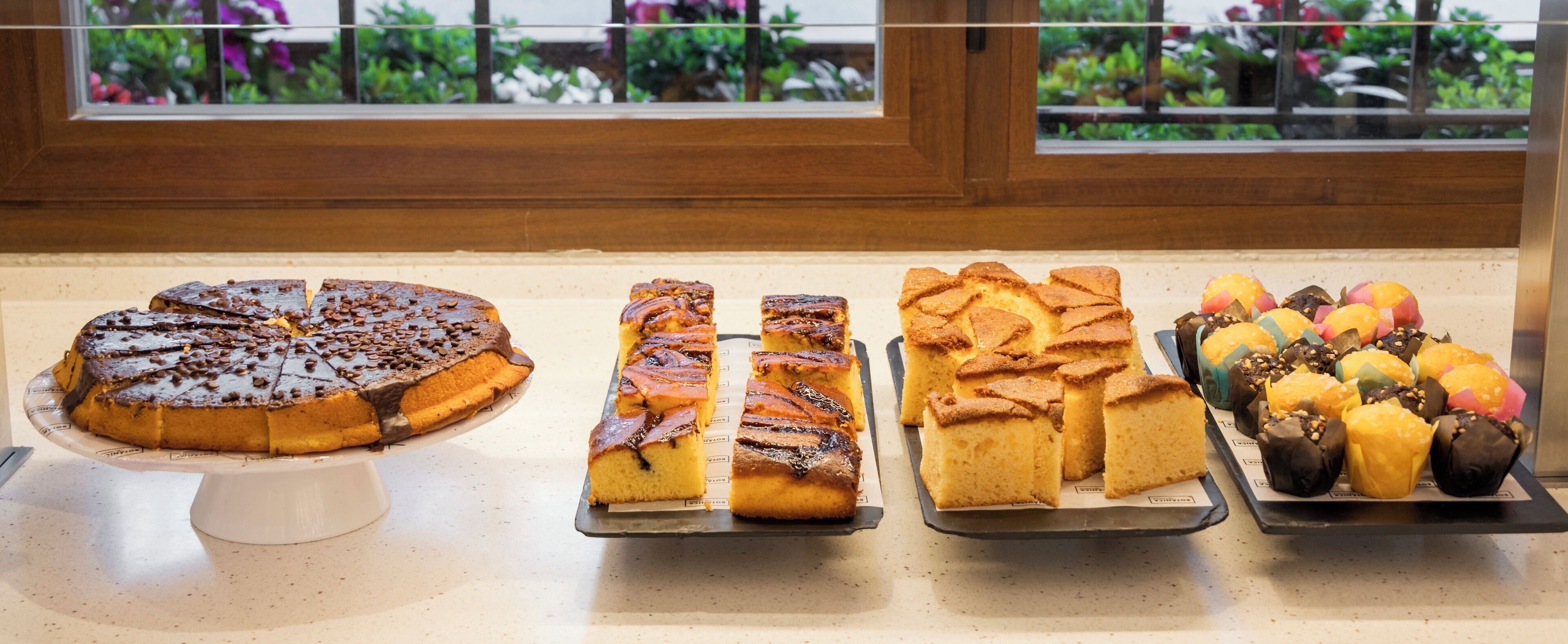 A variety of baked goods displayed on trays in a bakery setting.