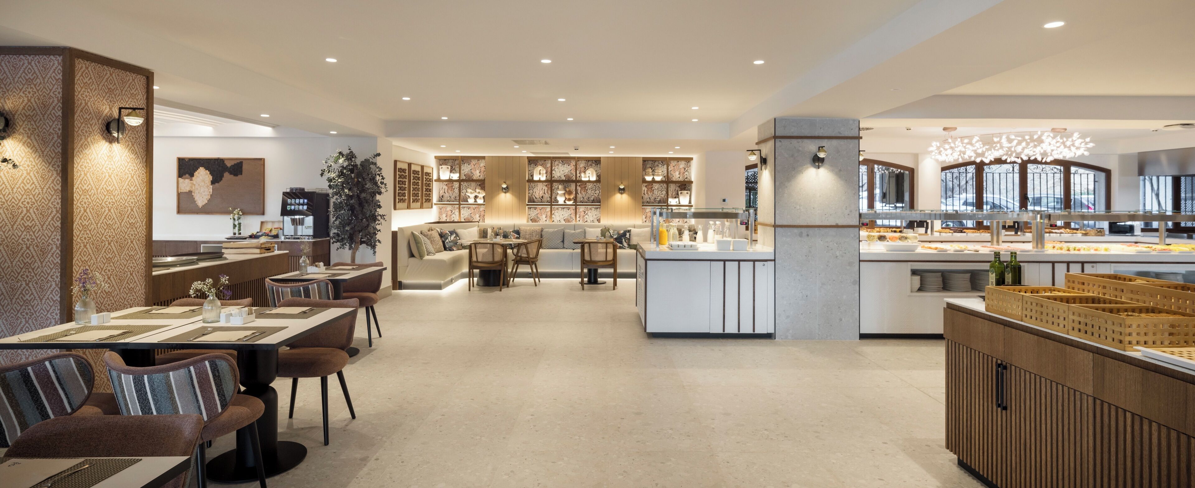 A modern hotel lobby with a central seating area, a coffee bar, and a buffet.