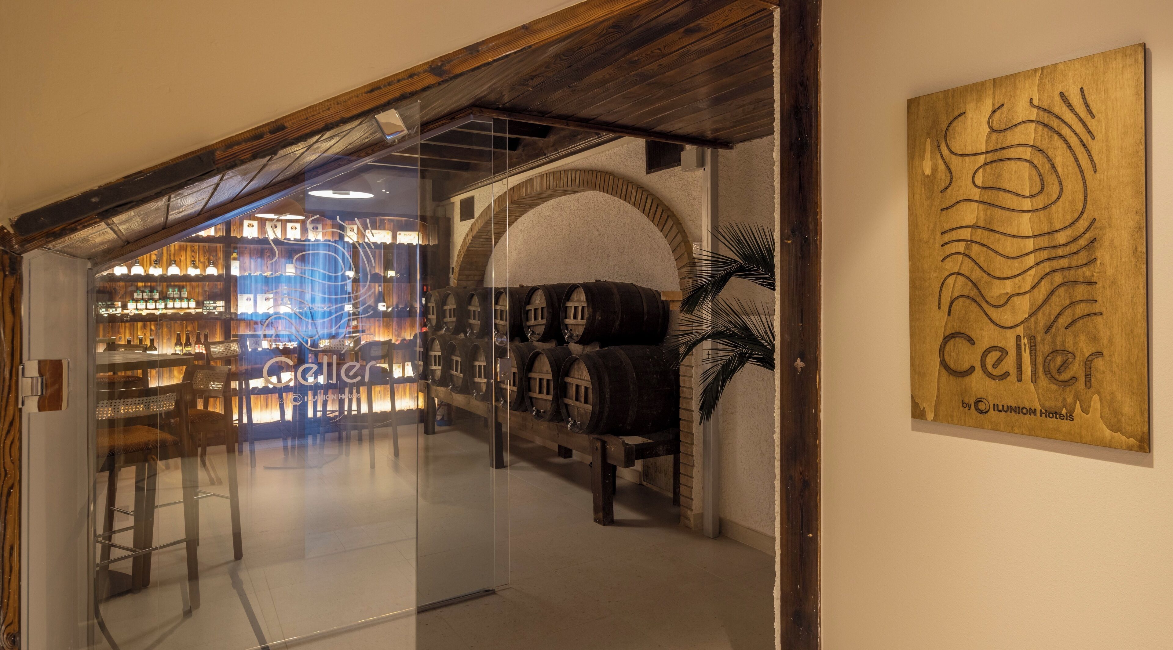 Eine Hotelhalle mit Glastrennwand, Weinkisten aus Holz und einem Holzschild mit dem Hotelnamen.