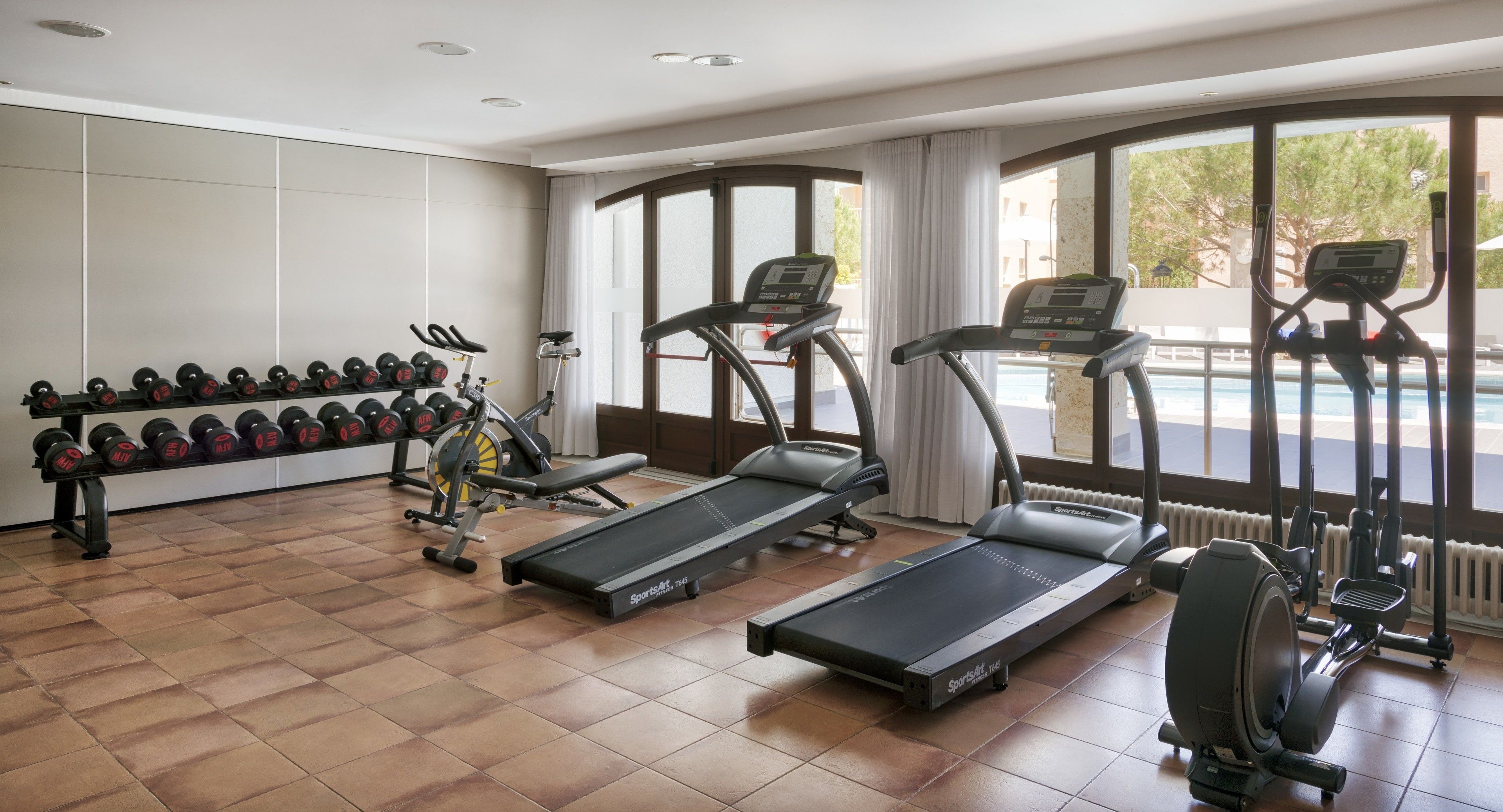 A gym with treadmills, dumbbells, and exercise equipment.