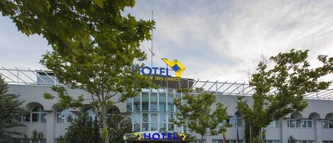 Un hotel con un letrero llamativo, fachada de edificio moderna y zona de estacionamiento.