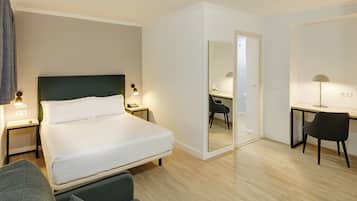 Ein Hotelzimmer mit Bett, Nachttischen, Schreibtisch, Stuhl und Spiegel.
