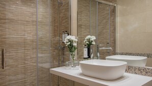 Un baño moderno con un lavamanos grande de color blanco, una cabina de ducha de vidrio y un espejo que refleja la habitación.