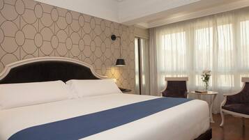 Una habitación de hotel con una cama grande, una mesa redonda con lámpara y una silla.