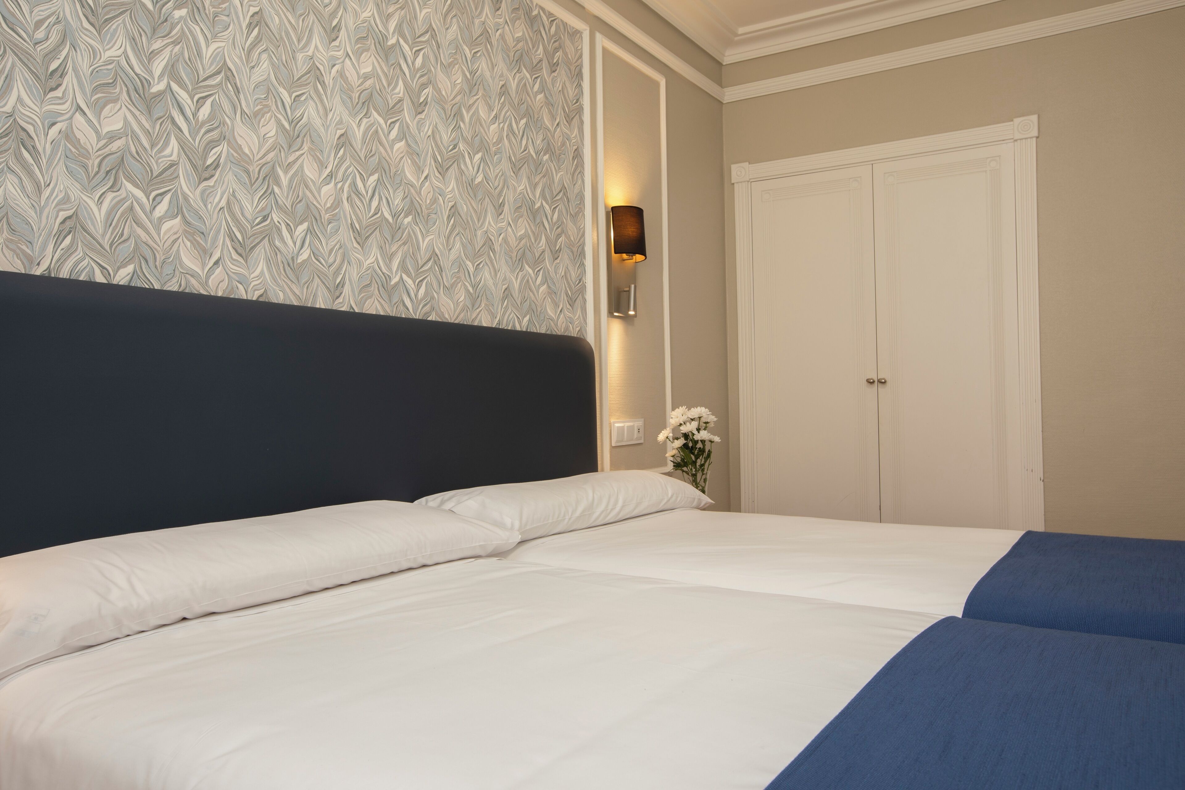 Een hotelkamer met een groot bed, een wandlamp en een deur.